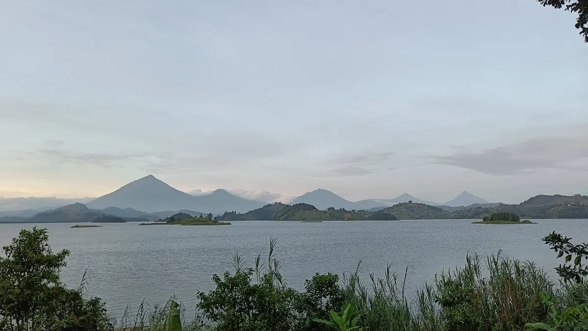 Keten van vulkaantoppen achter het kalme water en de kleine eilanden van Lake Mutanda